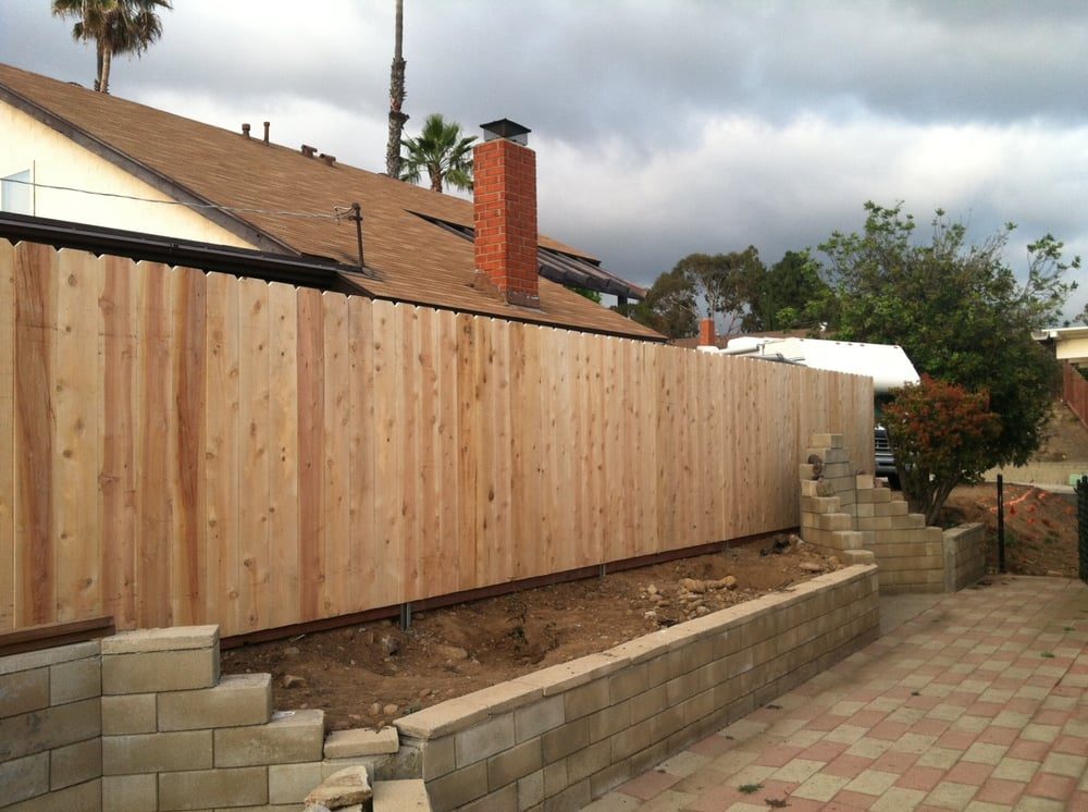 Tall cedar privacy fence above a block retaining wall